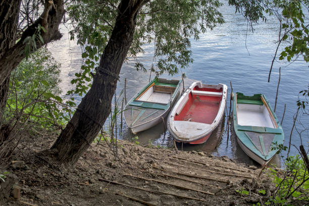 The Tisa River flows silently through the plain. Fishing boats are tied to the shore and waiting for the fishermen.