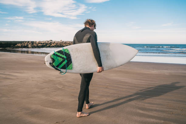istock Surfer standing in the ocean with his surfboard. 1251759035