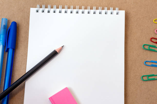 istock composition with notebook blank page colorful pencil, marker and pen mock-up Back to school concept with stationery office supplies on a kraft cardboard background 1251761085