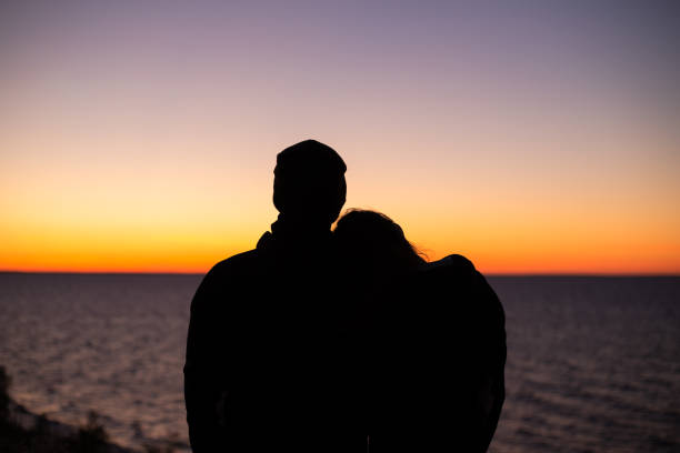 siluetas de una pareja en el fondo del lago y el cielo de la puesta de sol - finland lake summer couple fotografías e imágenes de stock