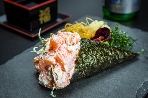 Sushi. Traditional Japanese cuisine, premium salmon Temaki with cream cheese decorated in an elegant setting.