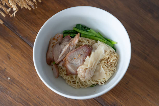 istock Chinese style Egg noodle with red roast pork, dumplings or wonton and condiments 1251773976