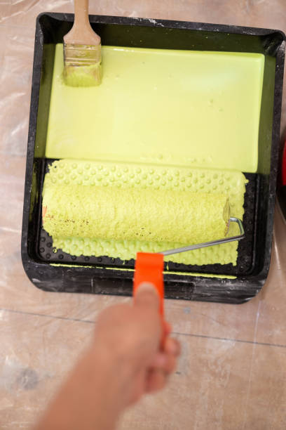 istock Painter with rollers in the tray with green paint 1251775150