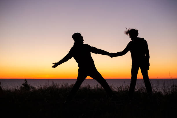 siluetas de una pareja en el fondo del lago y el cielo de la puesta de sol - finland lake summer couple fotografías e imágenes de stock