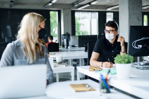 istock Young people with face masks back at work or school in office after lockdown. 1251819868
