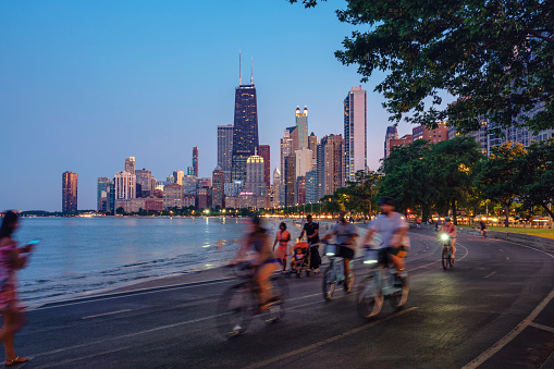 People riding bicycles at night with Chicago skyline in background