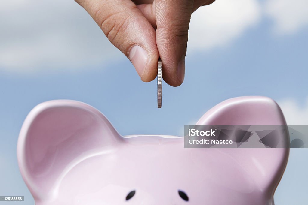 Saving Male hand putting a coin into piggy bank Savings Stock Photo