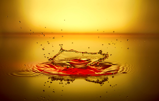 a splash of red liquid with a reflection on a yellow background