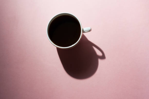 istock One white cup of coffee with a long deep shadow on a dark texture pink background. Top view, flat lay 1251850986