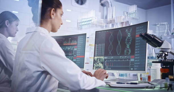 equipo de investigación femenino que estudia mutaciones en el adn. pantallas de ordenador con hélice de adn en primer plano - adn fotografías e imágenes de stock