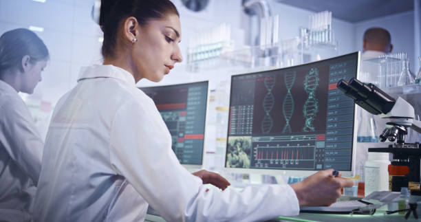 istock Research team studying DNA mutations. Computer screens with DNA helix in foreground 1251892824