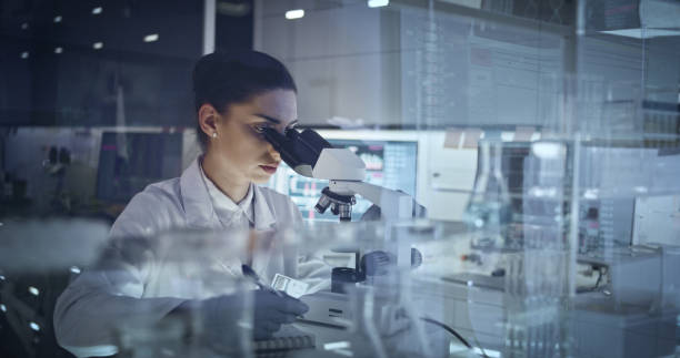 istock Female scientist working after hours. Research team in background 1251894565