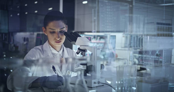 istock Female scientist working after hours. Research team in background 1251894602