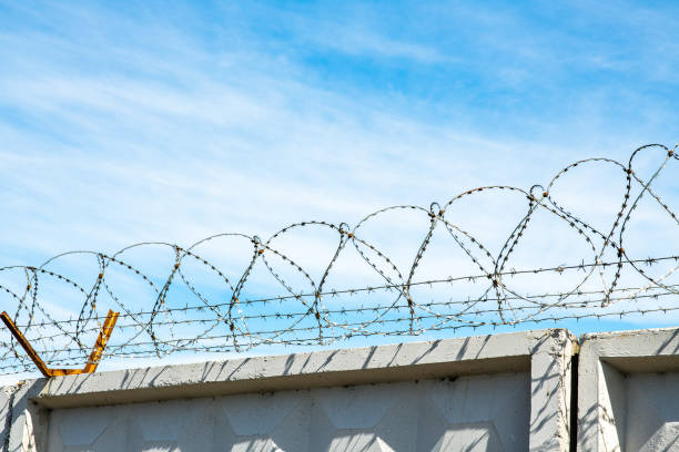 istock Barbed wire on the high wall on  top secret territory 1251897004