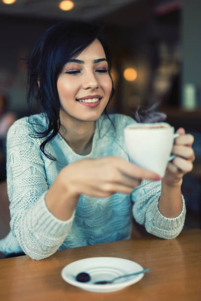 istock Stylish young woman drinking coffee at the cafe 1251898355