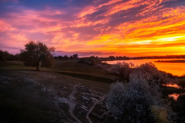 The clouds burst with sunrise colors over the trees and lakes of Loveland Colorado located in Larimer County