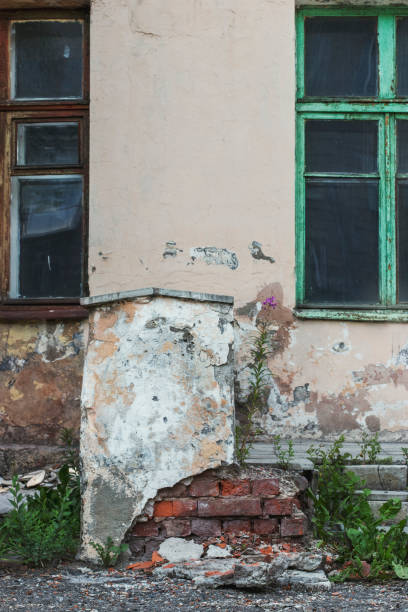 istock A dilapidated building overgrown with grass and bushes on a bright sunny day in summer. 1251925804
