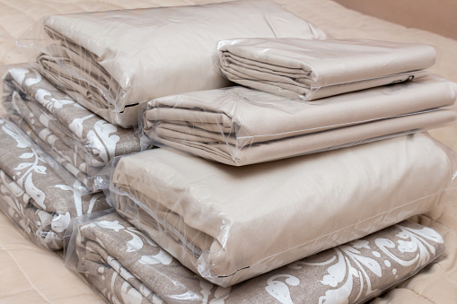 White and beige packed pile of the linen bedclothes blanket with pillow and bedding sheets