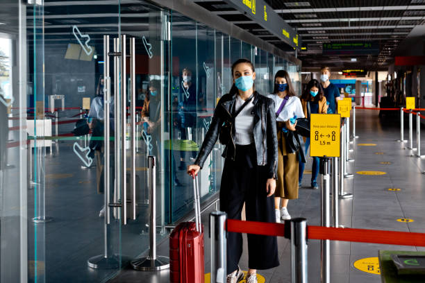 passagiers die n95 gezichtsmaskers dragen die in lijn bij luchthaventerminal wachten - airport stockfoto's en -beelden