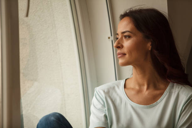 istock Woman looking through the window, deep in thought 1251946567