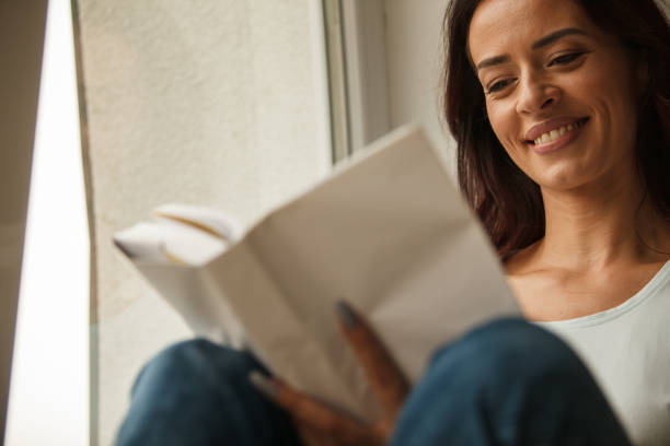 istock Happy woman smiling while reading an interesting book 1251947666