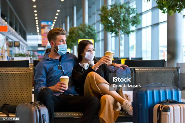 Young Couple Wearing N95 Face Masks Waiting In Airport Area Stock Photo - Download Image Now