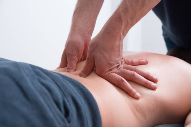Physical therapist pressing or pushing on lower back maknig deep massage stock photo