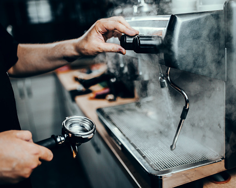 Hands Professional barista at work by an espresso machine - thick steam