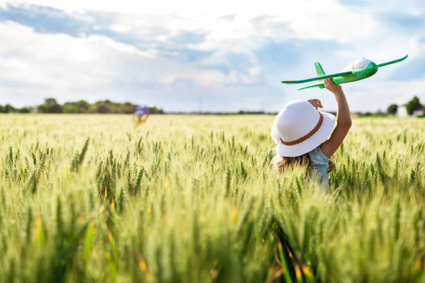 istock Little girl flying through green wheat field 1251961701