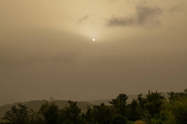 A gigantic plume of Sahara dust arrived from Africa over Caribbean islands, on its way to america. It is passing over Dominica for about a week at end of June, heaviest such cloud in some 50 years, making international news. Soon looks like a moon, and almost cloudless sky looks yellow from the sand dust.