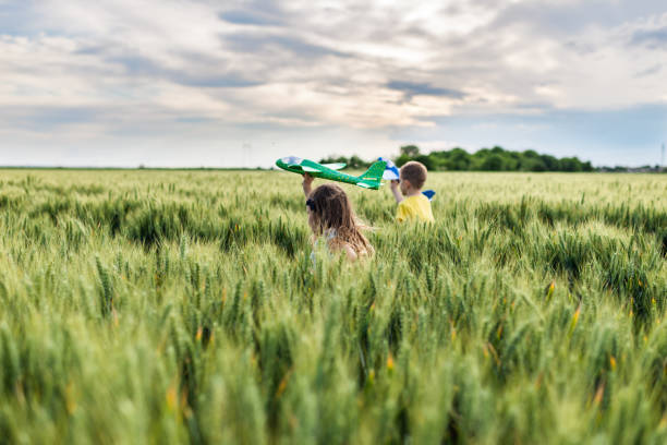 Children running through green wheat field