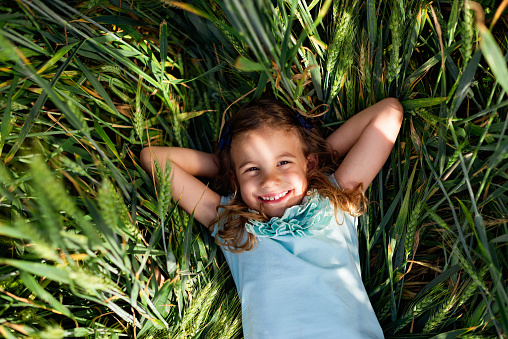 Adorable little girl in blooming dandelion meadow on beautiful spring day. Child having fun outdoors picking fresh flowers.