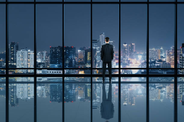 istock Businessman standing in modern office interior and looking to night city 1252013608
