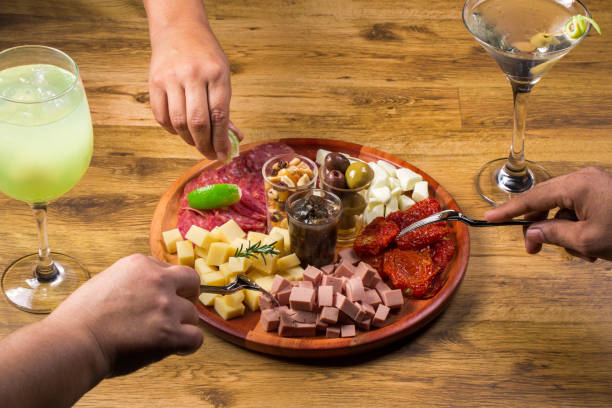 persone che mangiano tavola con antipasto.amici che mangiano e bevono insieme. vista dall'alto delle persone, festa, incontro, cena insieme, con tavola con vari antipasti e bevande alcoliche - delicatessen meat cold cuts chopped foto e immagini stock