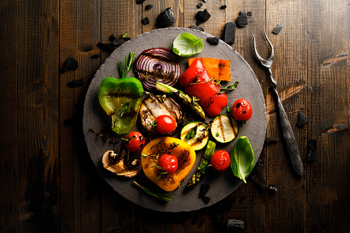 Grilled vegetables on rustic background with wrought iron fork.