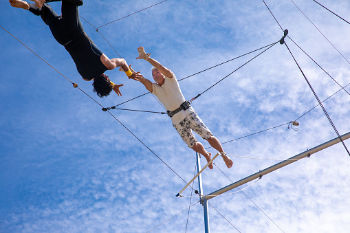 Active mature athlete flying in the sky for trapeze