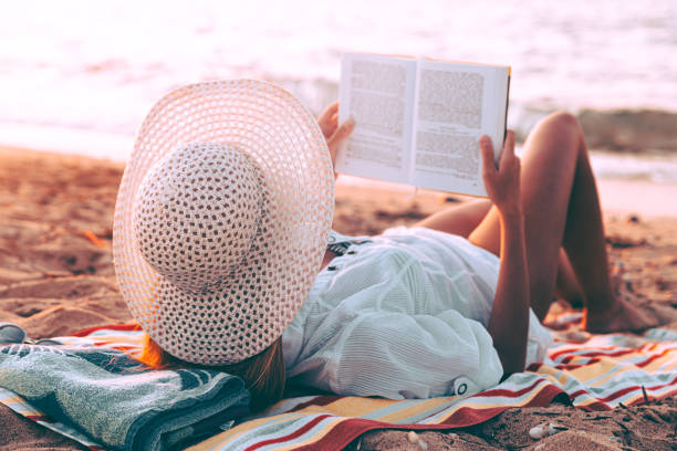 istock Woman reading book on the beach 1252093878