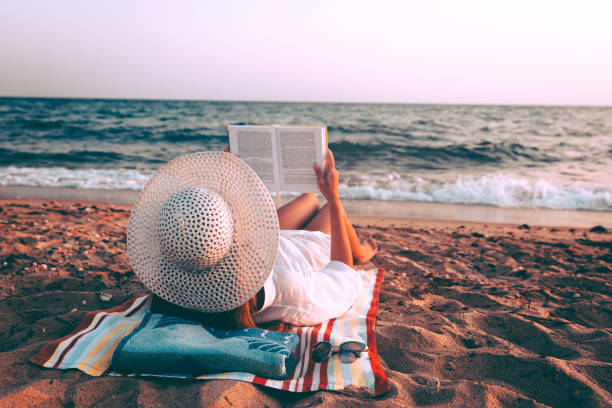 istock Woman reading book on the beach 1252094910
