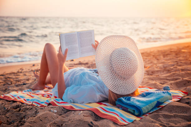 istock Woman reads book while relaxing on the beach 1252095431