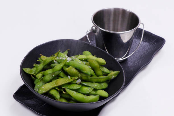 gekochte grüne sojabohnen in der hülse, die als edamame bekannt ist - soybean bean edamame pod stock-fotos und bilder