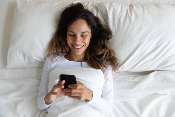 istock Happy young woman relax in bedroom using cellphone 1252119993