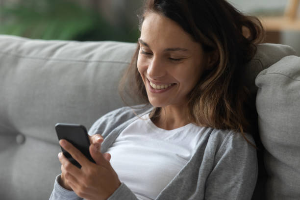 istock Happy millennial girl relax on couch using cellphone 1252120563