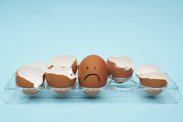 istock Chicken eggs in an egg holder. Full tray of eggs. Half an egg, egg yolk, shell. Emotion and facial expression painted on eggs. 1252122762