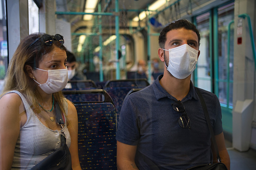two friends talking in subway wearing a mask while traveling