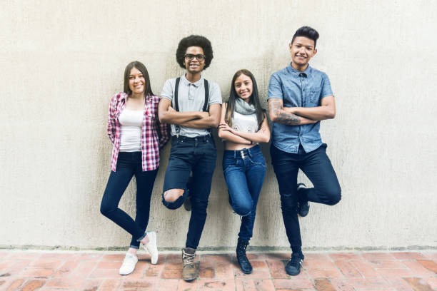 istock Happy diverse friends leaning against the wall smiling at camera 1252179101