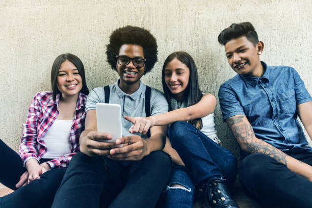 istock Young diverse friends checking their social media on smartphone while sitting on floor 1252179151
