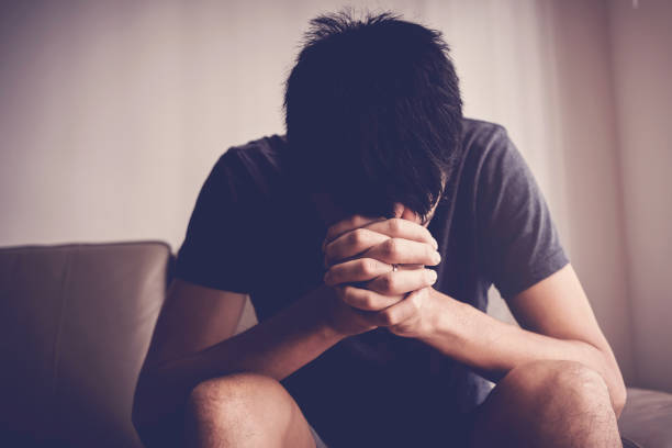 Depressed, despair and anxiety young man sitting alone and praying at home, mental health, men health, praying christian  concept Depressed, despair and anxiety young man sitting alone and praying at home, mental health, men health, praying christian  concept addiction stock pictures, royalty-free photos & images
