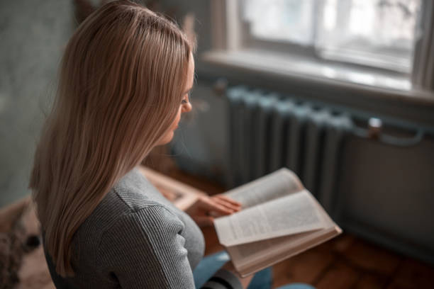istock The girl is sitting at the table and reading a book 1252205712