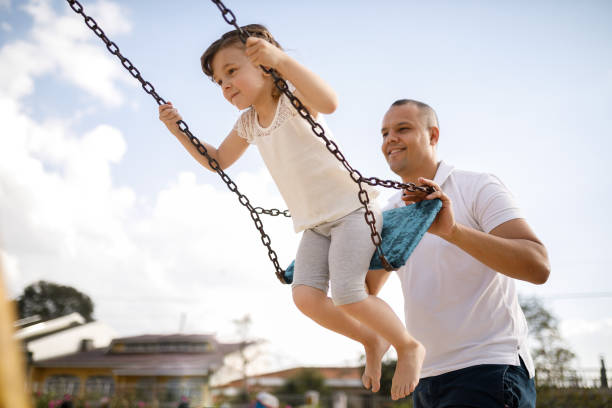 Father pushing his daughter on the swing