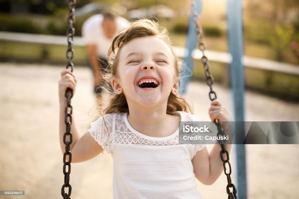 Chica sonriente jugando en el columpio - Foto de stock de Niño libre de derechos